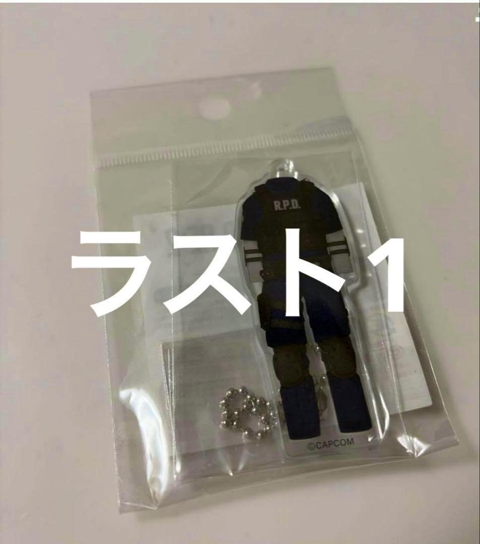 A sealed plastic bag containing an acrylic keychain of Leon in an R.P.D. outfit with a small ball chain visible.