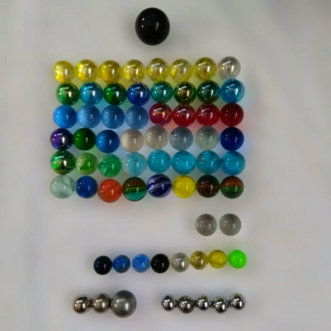 Multiple glass marbles and metal pachinko balls arranged on a white background.