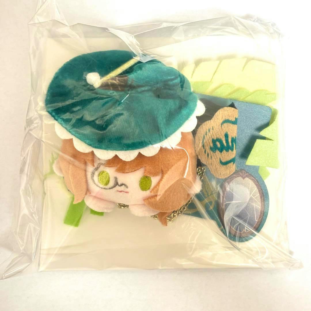 Photo of the リバース1999 カカニア ぬいぐるみ缶バッジ in plastic packaging, showing the plush badge's face, hat, attached chain, and backing card.