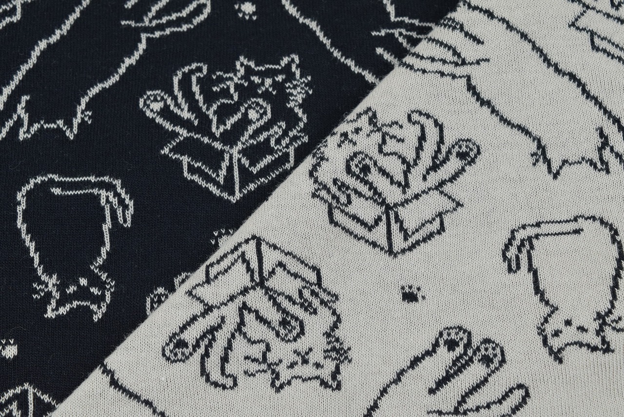 Close-up of the reversible jacquard knit fabric showing black and cashmere sides with the cat (nyanko) pattern.
