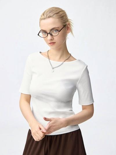 Model shown from the waist up wearing a white ribbed boat-neck cotton blouse with short sleeves.