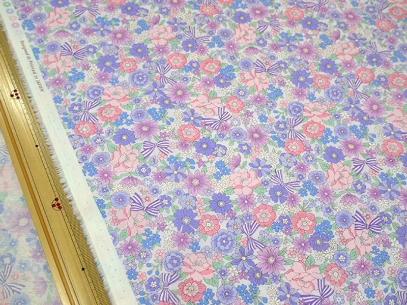Flat photo of the ribbon-and-small-flower printed broadcloth fabric with a ruler at the edge for scale.
