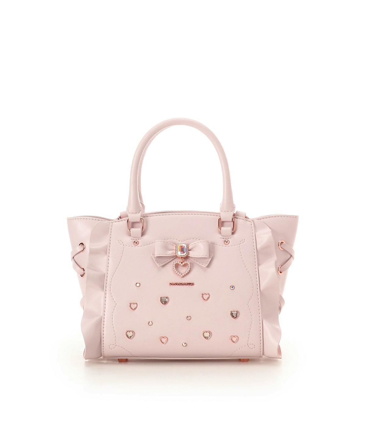 Front view of the pink cow leather bag showing a decorative bow, heart-shaped studs, ruffled sides, and dual handles.