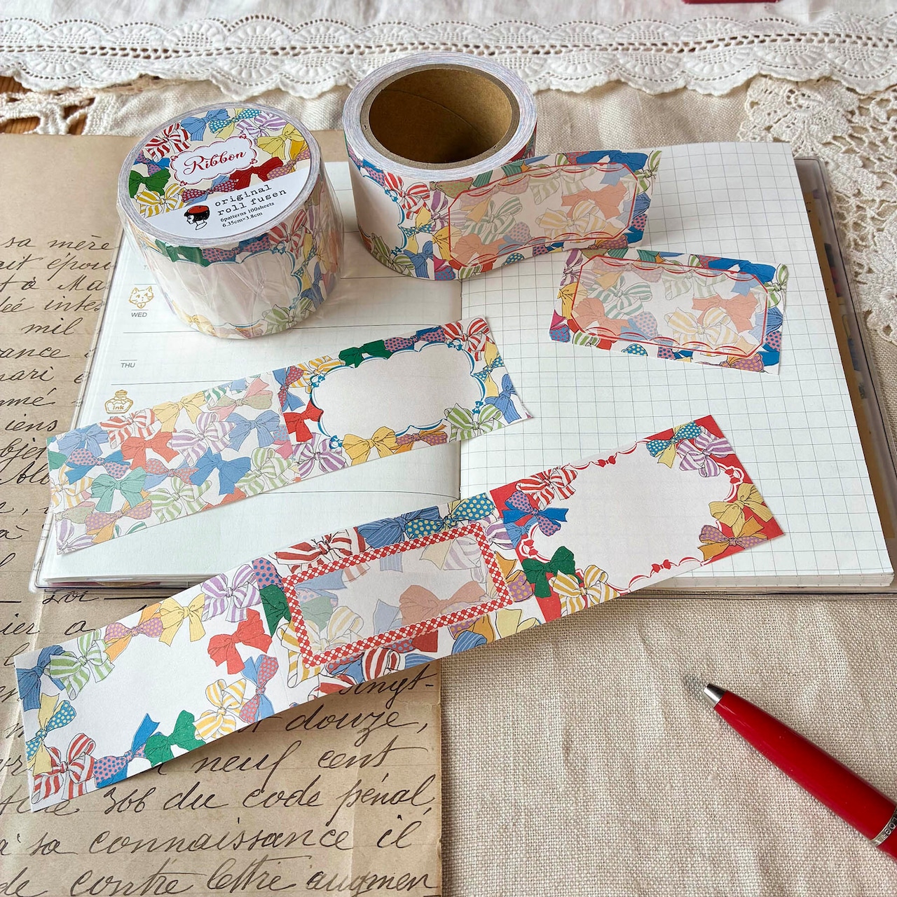 Ribbon-pattern roll sticky notes with several label stickers laid out on an open notebook.
