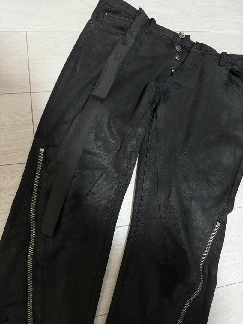 Black Rick Owens DRKSHDW spiral zip pants laid flat showing diagonal leg zippers and a button fly.