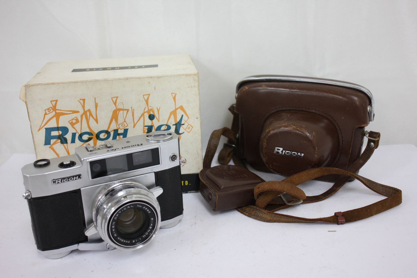 A Ricoh Jet 35mm film camera displayed with its original box and a brown carrying case.