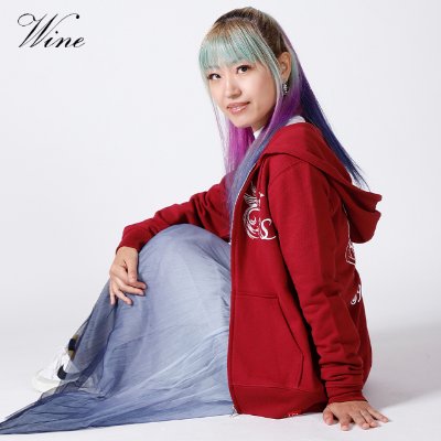 A seated woman wearing a wine-colored zip-up hoodie.