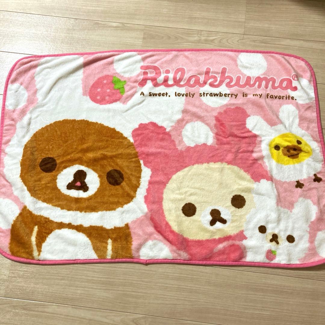 Pink polyester Rilakkuma and Korilakkuma strawberry blanket laid flat showing characters and the "Rilakkuma" text.