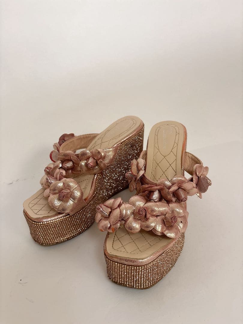 Pink-gold flower-motif platform sandals shown together on a plain background.
