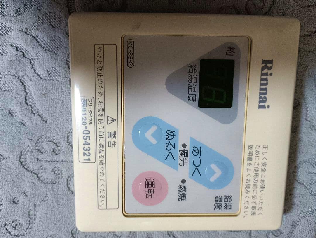 Front view of the Rinnai MC-33-2 water heater remote control showing the display, up/down buttons, and Rinnai logo.