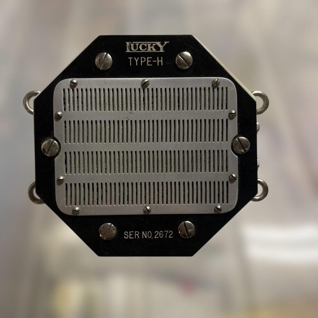 Front view of a vintage carbon microphone showing a metal grille, "LUCKY TYPE-H" label, and serial number.