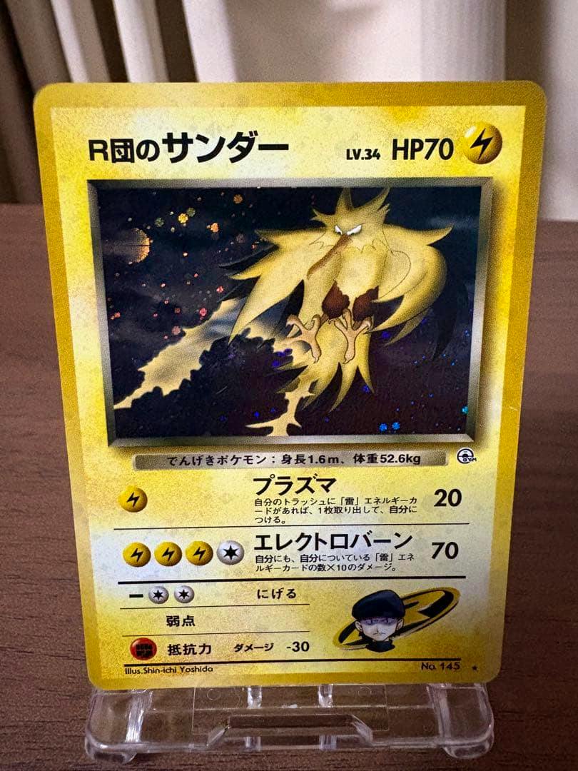 Front of the trading card 'R団のサンダー' showing the card artwork, HP and attack text, photographed upright on a small display stand.