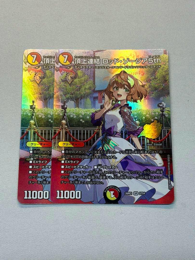 Photo of two holographic trading cards featuring an illustrated dragon-girl character on a white background.