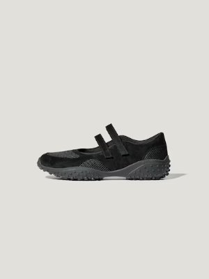 Side view of a black double-strap ballet sneaker by rokh on a plain gray background.