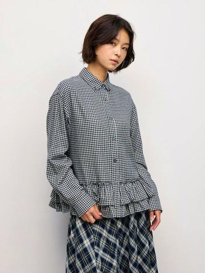 A model wearing the frill shirt in a small checked pattern with a ruffled hem.