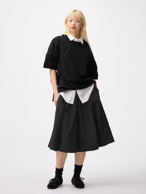 Model wearing a black women's skirt styled with layered shirt and sweater on a white background.