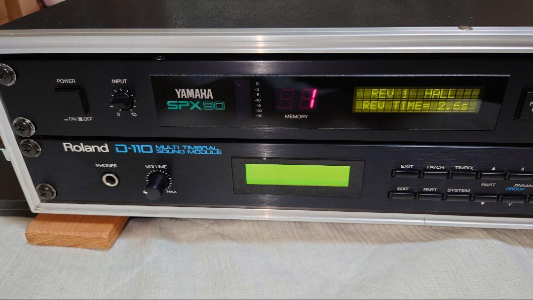 Close front view of a Roland D-110 multi‑timbral sound module installed in a rack beneath a Yamaha SPX90.