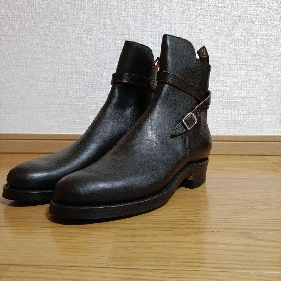 A pair of leather Jodhpur boots placed on a wooden floor.