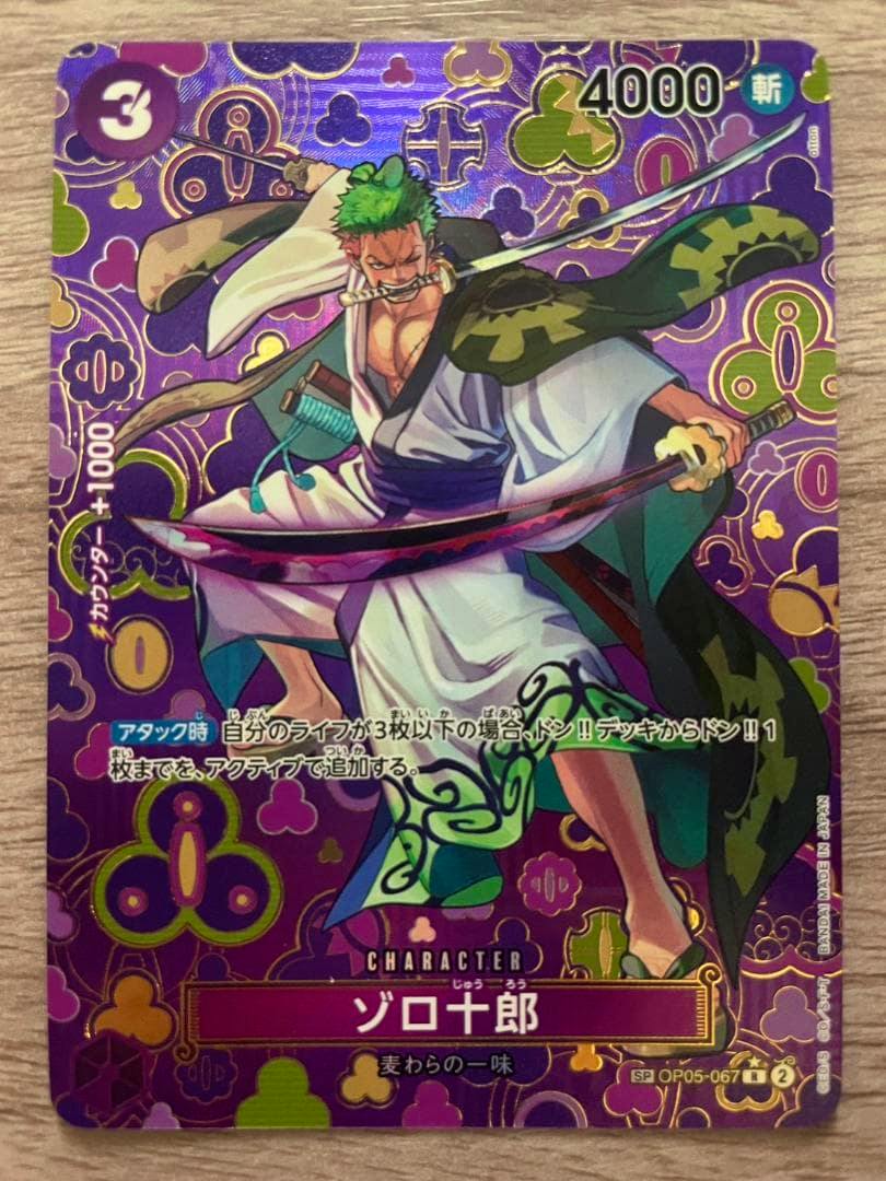 Front of the holographic One Piece trading card 「ゾロ十郎」 showing Zoro wielding a sword with Japanese text and a purple patterned background.