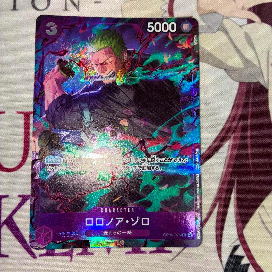 Photograph of the holographic One Piece trading card ロロノア・ゾロ (OP09-076) showing the card front with a 5000 stat and purple border.