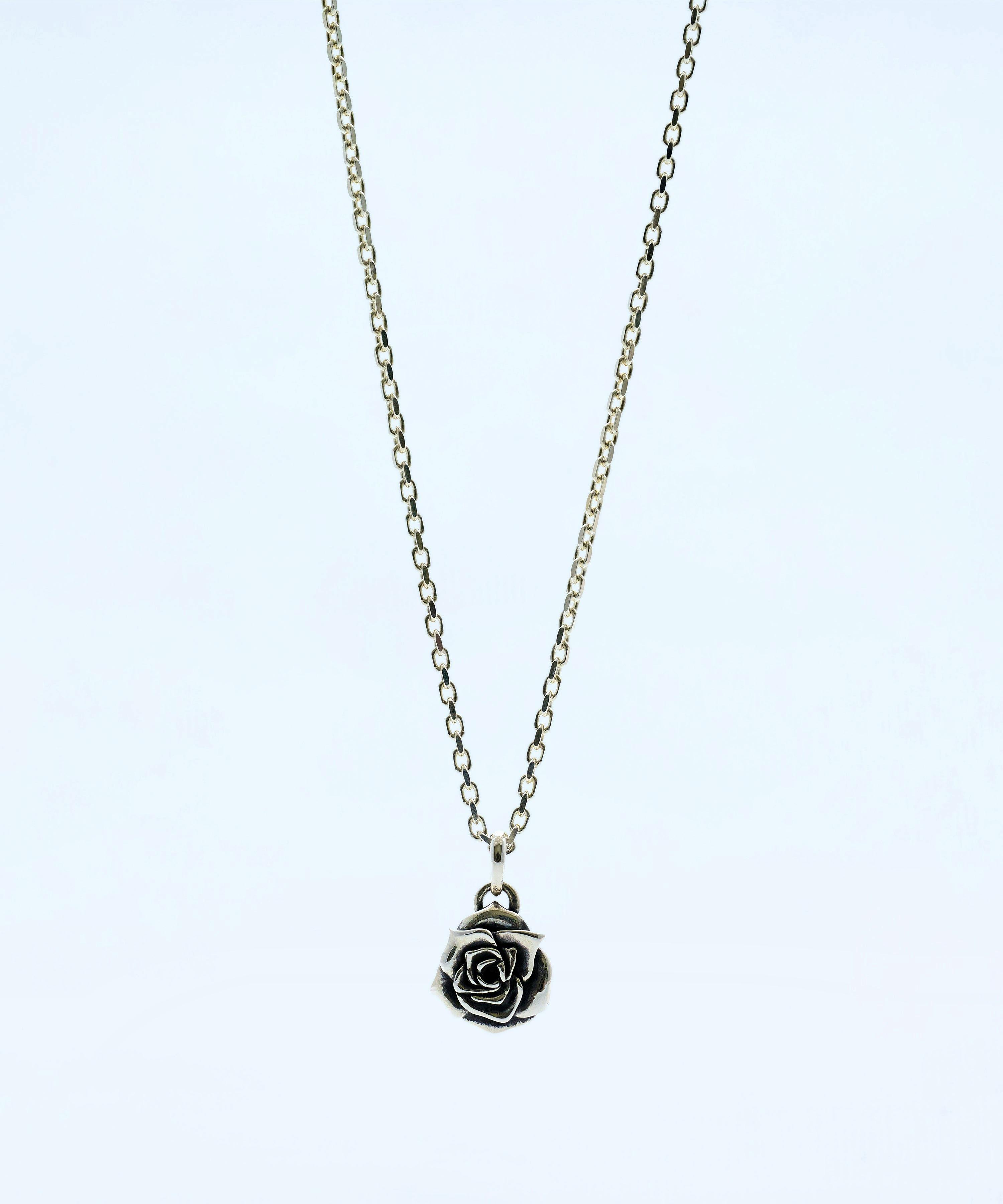 Silver rose pendant necklace (sv925) hanging on its chain against a white background.