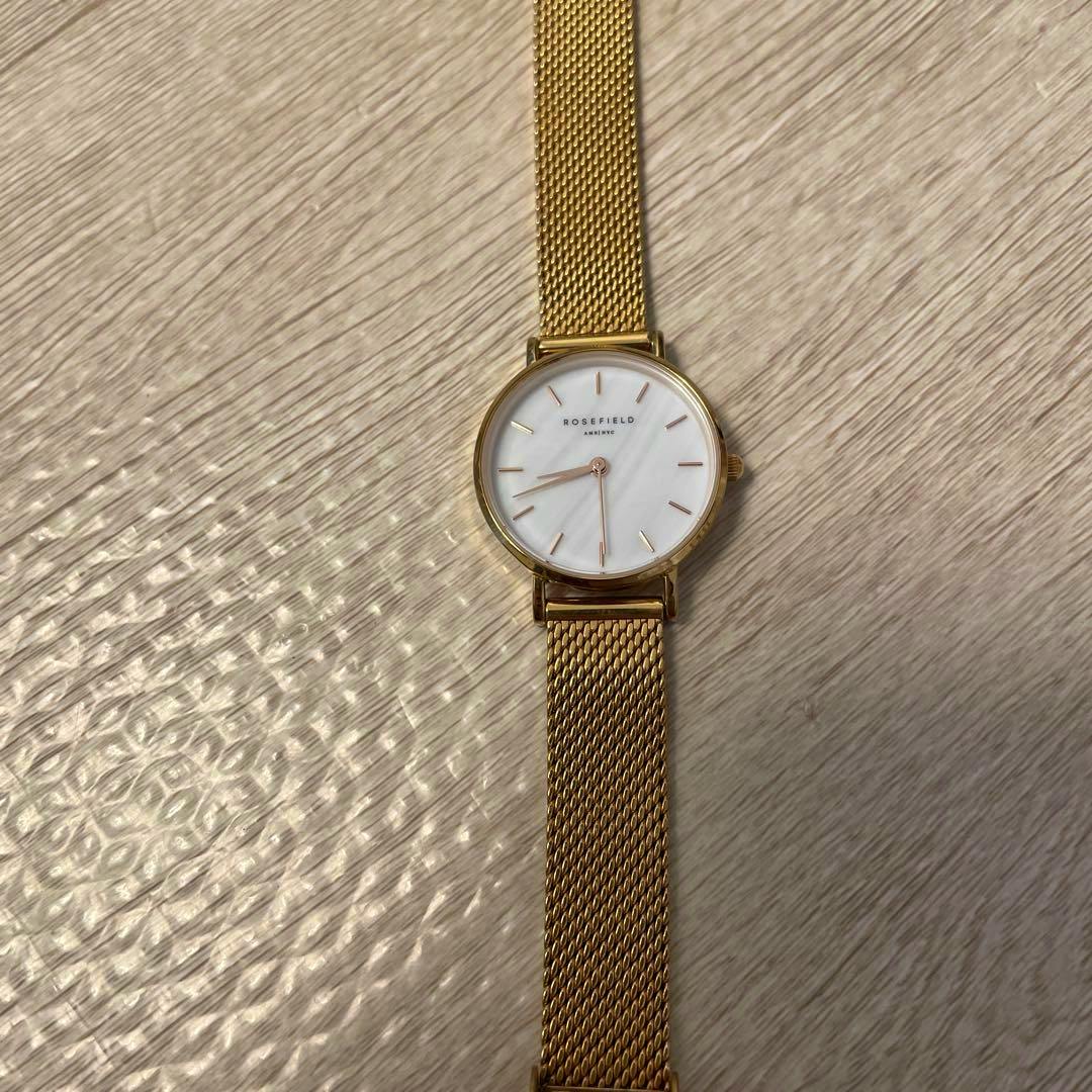 A ROSEFIELD women's pink gold mesh-strap wristwatch laid flat on a textured surface.