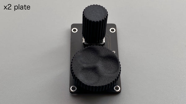 A black rectangular rotary encoder plate (for claw44v3/wings42) with two knurled knobs mounted on the PCB against a gray background.