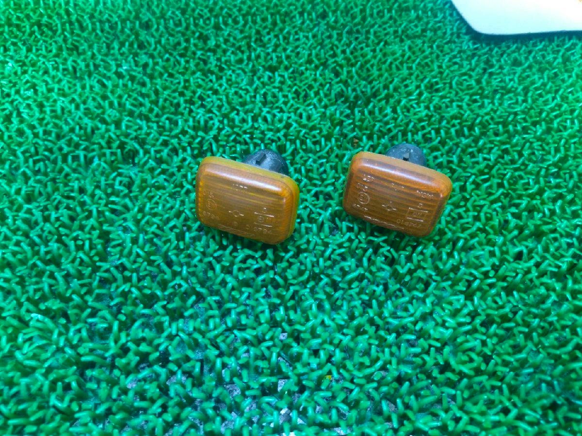 Two amber rectangular car front turn signal/side marker lenses shown on a green textured mat.