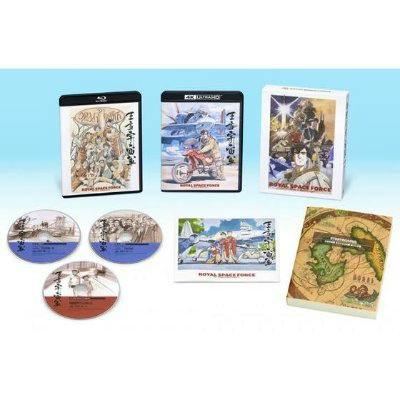 Laid-out product photo of the 4K remaster memorial box set showing multiple discs, two disc cases, an outer slipcase, and printed booklets.