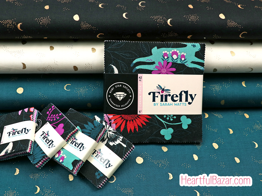 Firefly branded cotton fabric charm squares displayed on teal fabric with coordinating fabric bolts in the background.