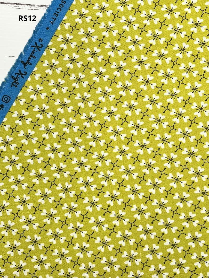 Yellow-green dyed cotton fabric with small white heart-clover pattern and a blue selvedge printed with RS12.