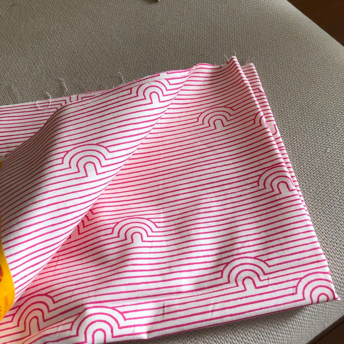 Folded Ruby Star Society cotton fabric in dark pink showing irregular stripe lines with small arch/rainbow motifs.