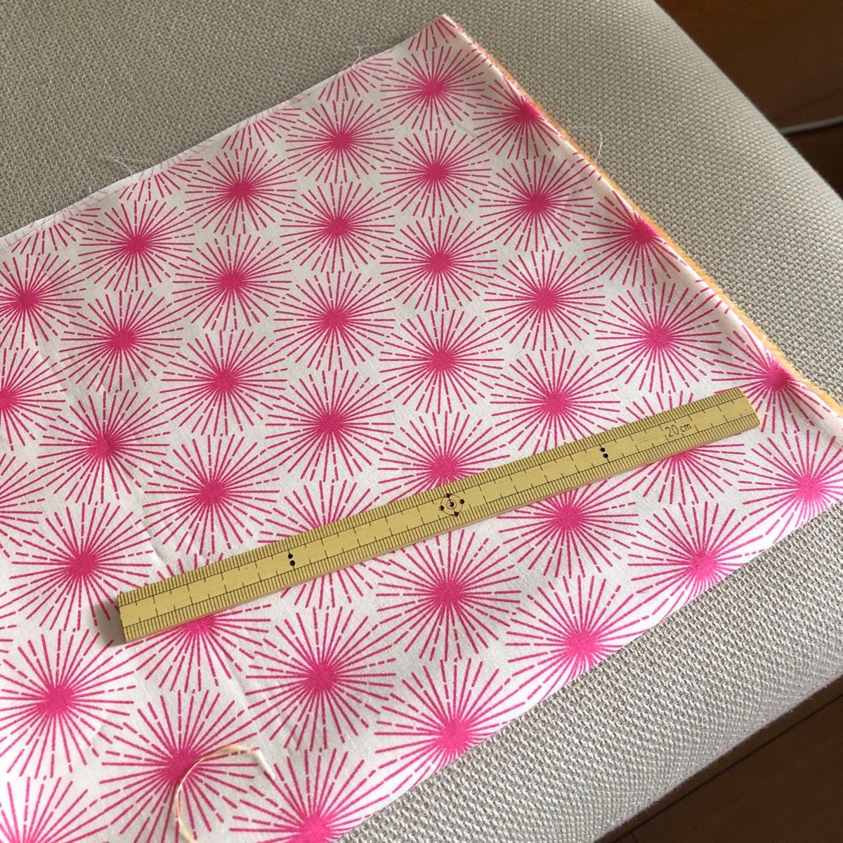 Dark pink firework‑like starburst patterned Ruby Star Society cotton fabric laid flat with a ruler for scale.