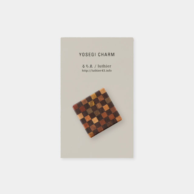 Dark brown square yosegi wooden keychain charm with a checkerboard pattern displayed on a product card labeled "YOSEGI CHARM".