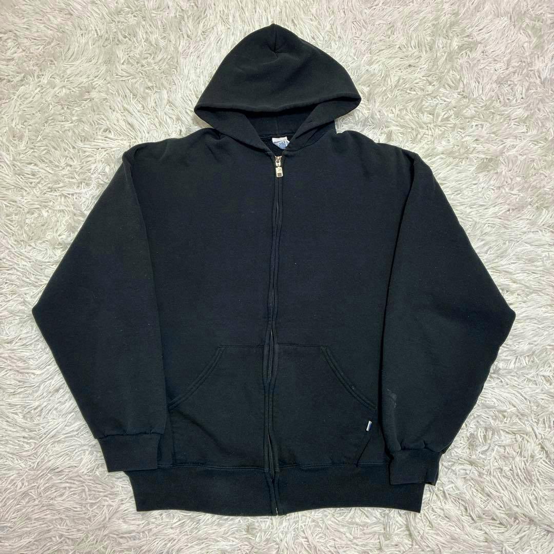 Black Russell Athletic zip-up hooded sweatshirt laid flat on a light textured rug.