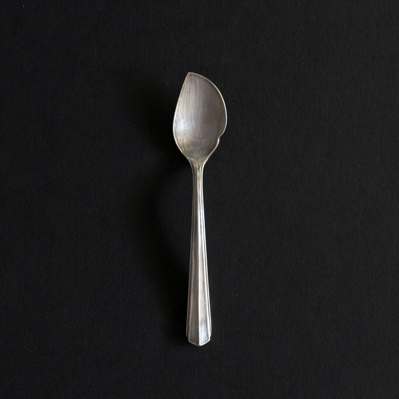 Full-length stainless steel cake spoon on a black background.
