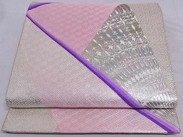 Folded silk obi for kimono showing pink, purple, and silver woven geometric and floral patterns.