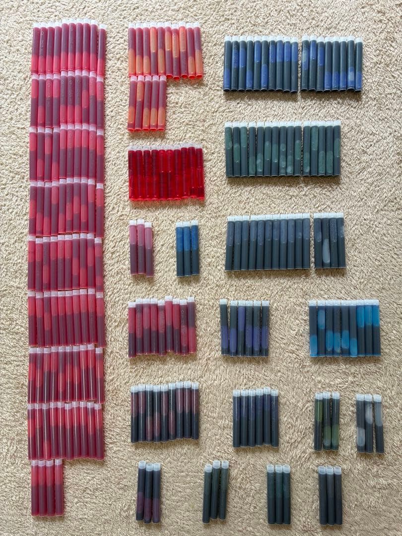 Multiple fountain pen ink cartridges in assorted colors laid out on a carpeted surface.