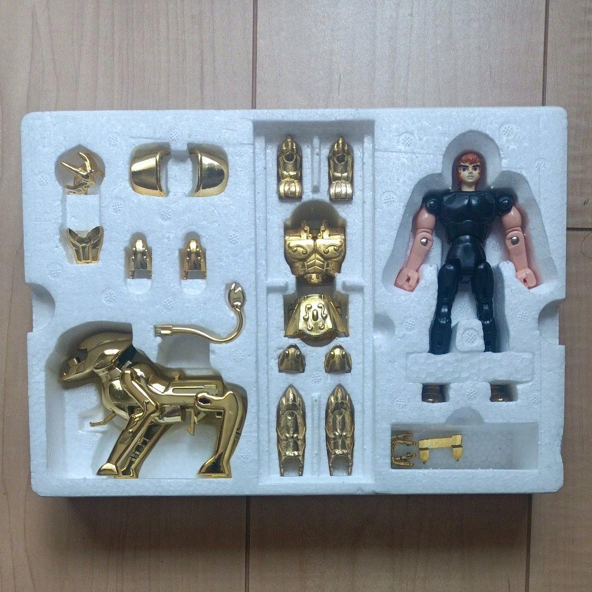 Styrofoam tray containing the Leo Cloth figure body alongside separate gold-colored armor pieces and a gold lion part.