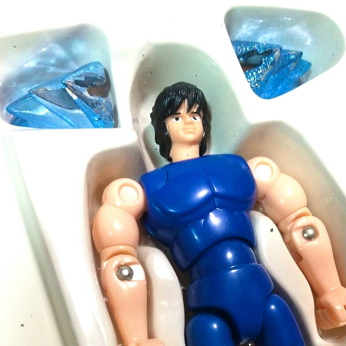Close-up of the plastic Saint Seiya figure torso and arms in blue armor with separate blue glitter armor pieces in a white plastic tray.