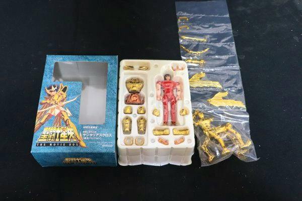 Opened product box with the molded tray containing the Saint Seiya (Sagittarius) figure and multiple gold armor parts in plastic packaging.