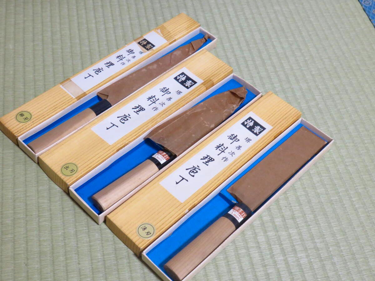 Three chef knives in their boxes with blades partially wrapped, shown on a tatami mat.