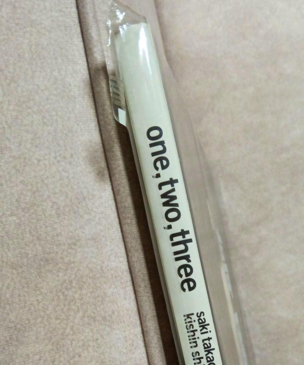 Photo of the book spine showing the title "one, two, three" in shrinkwrap.