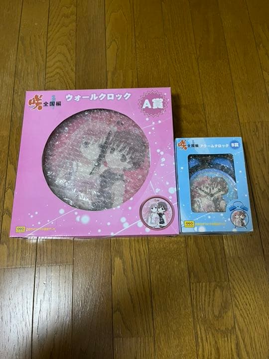 Boxed '咲-Saki- 全国編' wall clock and a boxed alarm clock placed on a wooden floor.