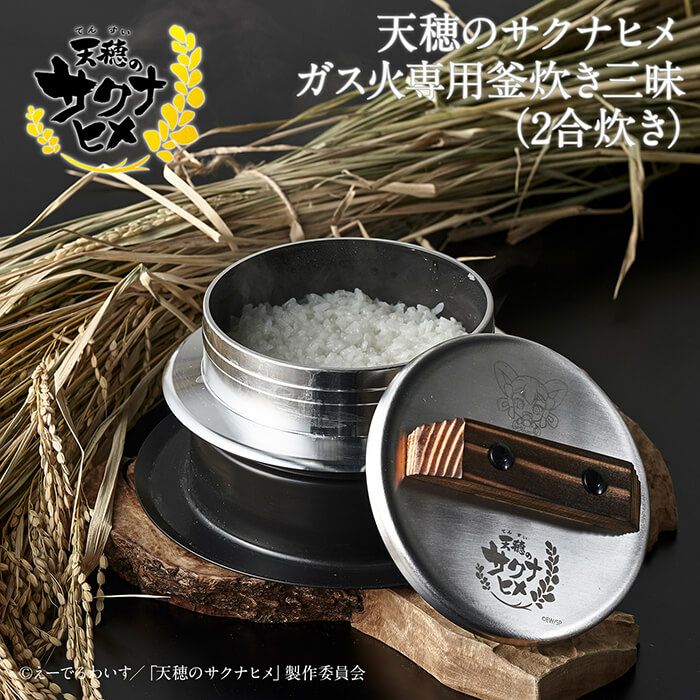 Silver metal two-part rice pot with lid and inner bowl filled with cooked rice, shown on a wooden surface with rice stalks and a printed logo on the lid.