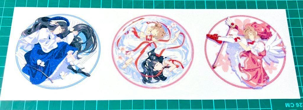Photograph of the three round sakura-themed paper stickers on a white backing placed on a green cutting mat.