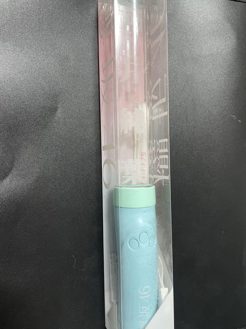 Pen light for 櫻坂46 member 向井純葉 with a light blue-green handle and clear tube inside a plastic sleeve.