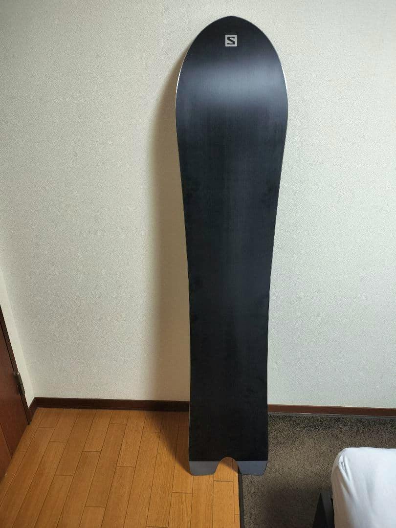 Full-length view of the snowboard's black base with a Salomon logo near the tip.