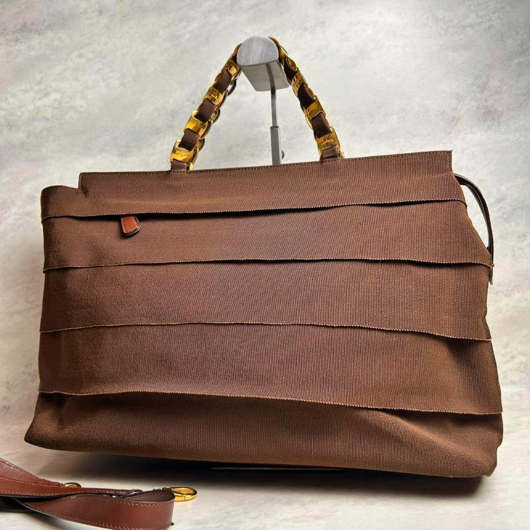 Brown Ferragamo 2way nylon tote bag shown front-facing with gold chain-accented handles and a detachable strap visible.