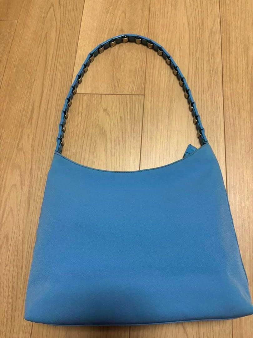 Blue Salvatore Ferragamo one-shoulder cow leather bag with a chain-linked shoulder strap lying on a wooden floor.